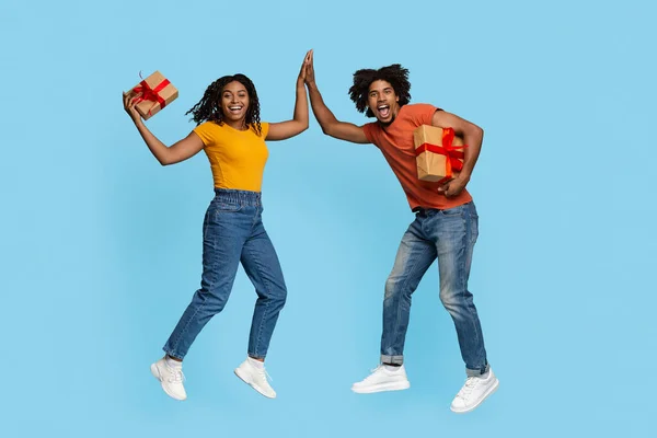 Emotionaler schwarzer Mann und Frau mit Geschenken, die High Five geben — Stockfoto