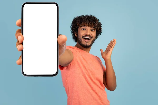 Эмоциональный кудрявый индиец показывает мобильный телефон с пустым экраном — стоковое фото