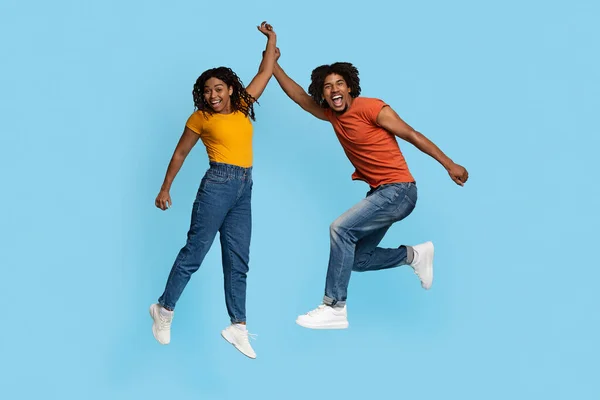 Emotional african american couple celebrating success on blue — Stock Photo, Image