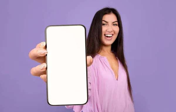 Hermosa mujer joven demostrando gran teléfono inteligente en blanco en su mano — Foto de Stock