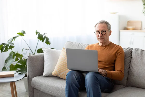 Confident casual mature man using laptop at home — Stock Photo, Image