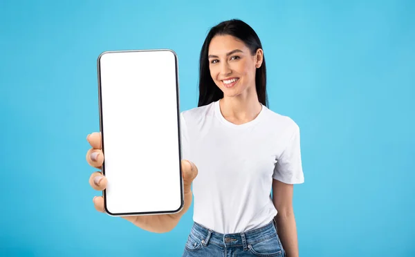 Joyeux jeune femme démontrant grand téléphone portable avec écran blanc, montrant l'espace pour votre conception, maquette — Photo