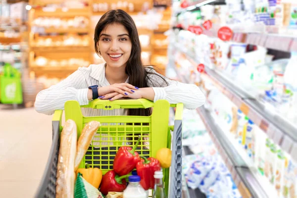 슈퍼마켓에서 카트를 가지고 쇼핑하는 행복 한 중동 여자 — 스톡 사진