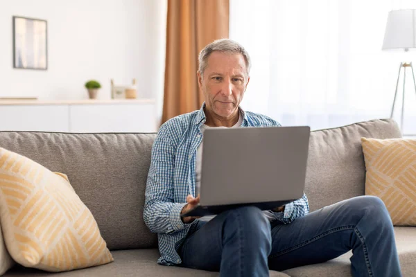 Confiante casual maduro usando laptop em casa — Fotografia de Stock