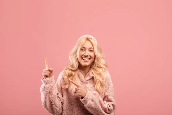 Retrato de mujer feliz señalando dos dedos hacia arriba en el espacio libre, la publicidad de su texto o promo, fondo rosa — Foto de Stock