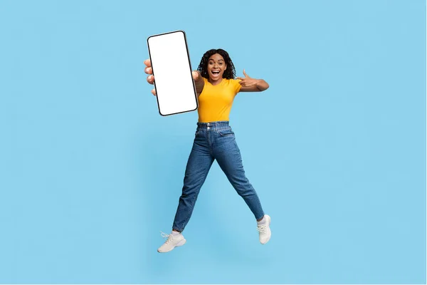 Emocionada mujer afroamericana saltando con smartphone, maqueta —  Fotos de Stock