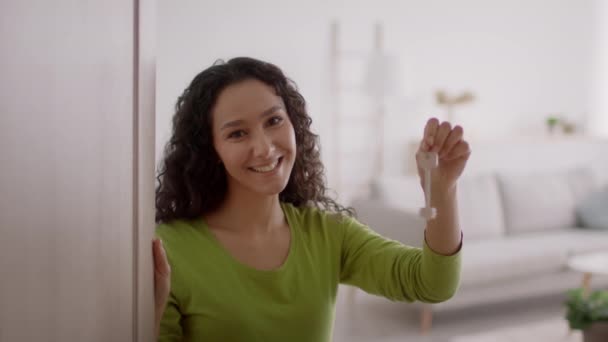 Glada Mellanösternkvinnan visar nyckel stående i dörröppningen inomhus — Stockvideo