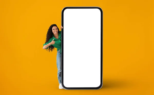 Glad dam kikar ut bakom Big Blank Smartphone och visar tummen upp — Stockfoto