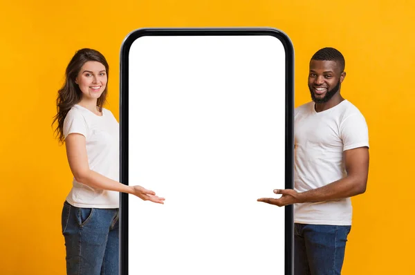 Glad Interracial Par Peka på Big Blank Smartphone med vit skärm — Stockfoto