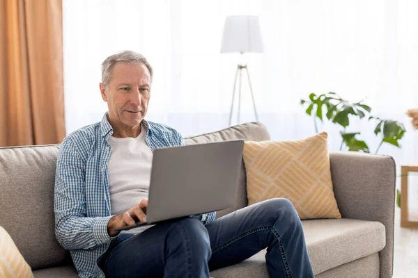 Confiado casual madura usando el ordenador portátil en casa —  Fotos de Stock