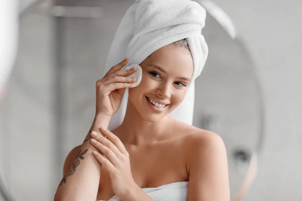 - 안녕 하 세요. 아름다운 여인 이 목욕 후 수건을 머리에이고 집에 있는 무명 패드로 얼굴을 닦고 있다 — 스톡 사진