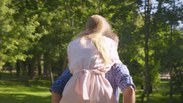 Безтурботна пара середнього віку в любові грає разом, чоловік скарбуючись сміється жінка в зеленому парку, відстежуючи постріл — стокове відео