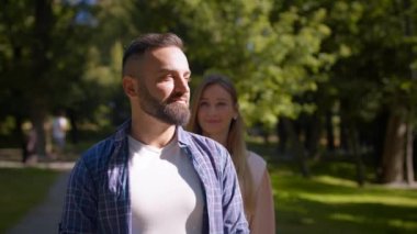 Mutlu adam kız arkadaşını bekliyor, neşeli kadın gözlerini kapatıyor ve yaz parkında yanaklarını öpüyor, boş yer var.