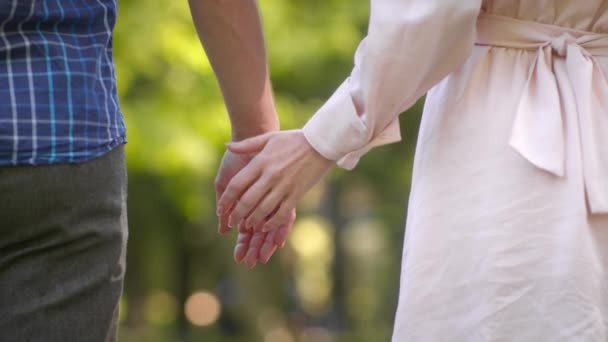 Понятие любви и связи. Неузнаваемая влюбленная пара, держащаяся за руки, стоящая вместе на улице, замедленная съемка — стоковое видео