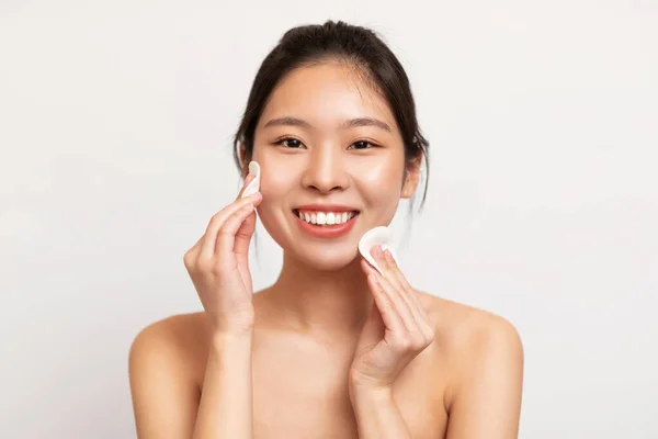 Ung asiatisk kvinna som rengör ansiktet med bomullspads — Stockfoto