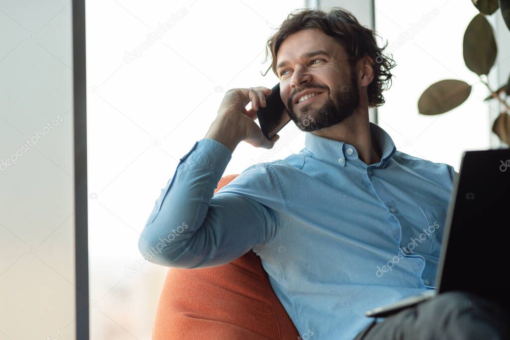 Smiling man working and talking on phone at office