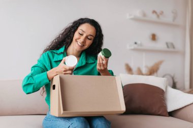 Skincare Kozmetik 'i elinde tutan mutlu bayan eve teslim kutusunu açıyor.