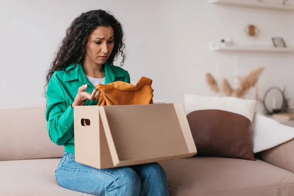 Csalódott nő vásárló gazdaság ruhák kicsomagolása doboz ül otthon — Stock Fotó
