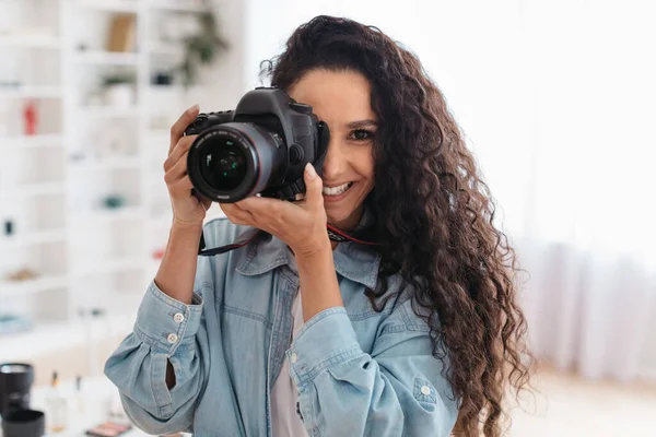 Profissional fotógrafo senhora tomando foto sorrindo segurando fotocâmera em pé dentro de casa — Fotografia de Stock