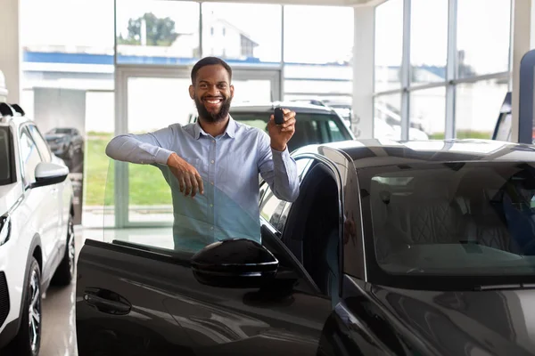 Happy Black Man Holding Car Keys, Autó mellett áll a Kereskedői Központban — Stock Fotó