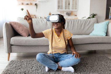 VR gözlüklü Afrikalı Amerikalı kadın yerde oturuyor.
