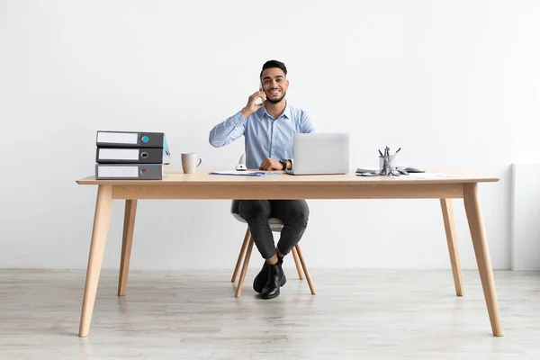 Sorrindo árabe homem trabalhando e falando ao telefone em casa — Fotografia de Stock
