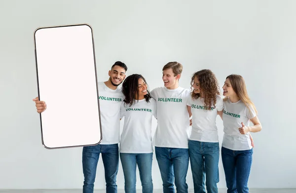 Excited diverse volunteering people showing white empty smartphone screen — Stock Photo, Image