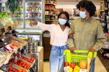 Kara Eşler marketten alışveriş yapıyor, maske takıyor ve marketten yiyecek alıyor.
