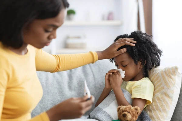 季節のインフルエンザ。自宅で病気の子供の世話をする黒のお母さんを心配 — ストック写真