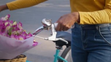 Tanımlanamayan siyahi bir kadının parkta bisiklet sürerken, zil çalarken, sepetin içinde, ağır çekimde...