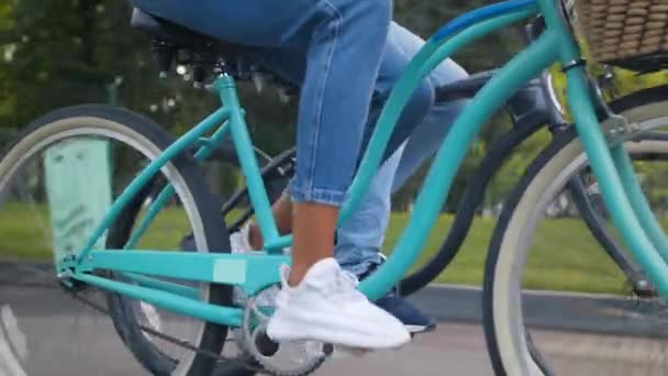 Nierozpoznawalny mężczyzna i kobieta jeżdżący na rowerach razem w parku, zbliżenie żeńskich nóg pedałujących na rowerze, strzał śledzący — Wideo stockowe