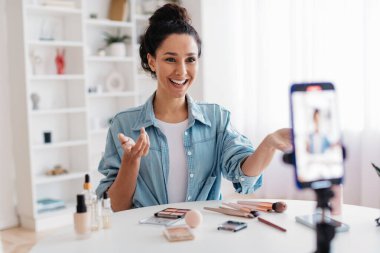 Makyaj blogcusu kadın cep telefonuyla konuşuyor. Evde video çekiyor.