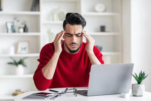 Arabo freelancer ragazzo avendo mal di testa mentre seduta a scrivania in casa ufficio — Foto Stock