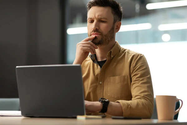 Serieuze zakenman die Laptop gebruikt Slecht nieuws lezen zittend op kantoor — Stockfoto