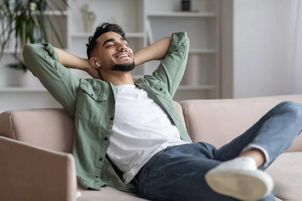 Guapo árabe chico en Airpods Easrphones escuchar música en casa — Foto de Stock