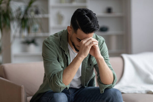 Portrait Of Depressed Middle Eastern Guy Sitting On Couch At Home