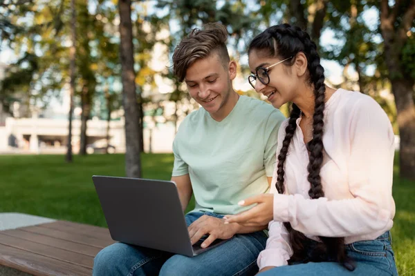 Amigáveis colegas de faculdade internacionais se preparando para palestras ao ar livre, sentado no parque ou campus universitário com laptop — Fotografia de Stock