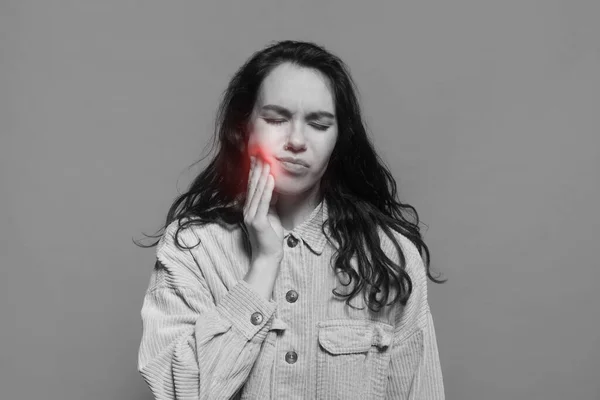 Занепокоєна тисячолітня біла жінка випадково страждає від зубного болю і притискає руку до щоки з запаленням — стокове фото