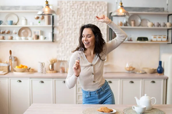 Hravá žena zpívající u spotřebiče jako imaginární mikrofon, tančící sama v kuchyni, volný prostor — Stock fotografie