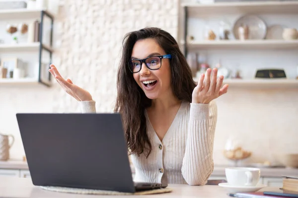 Retrato de mulher excitada fazendo videochamada online, conversando com colegas ou clientes via laptop, sentada na cozinha — Fotografia de Stock