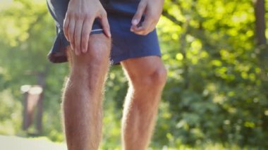 Tanımlanamayan koşucu koşuyor ve dizinde şiddetli bir ağrı hissediyor. Sabah parkta koşarken bacağına masaj yapıyor.