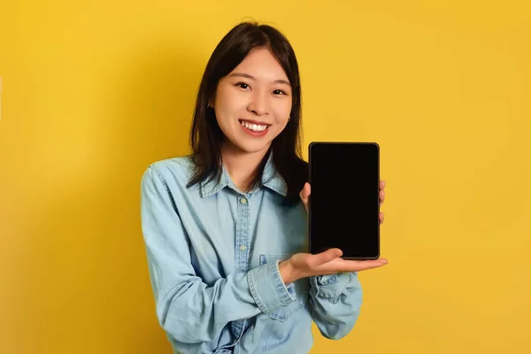Fröhliche junge Asiatin mit Tablet-Computer mit leerem Bildschirm auf gelbem Hintergrund, Attrappe für App oder Website — Stockfoto