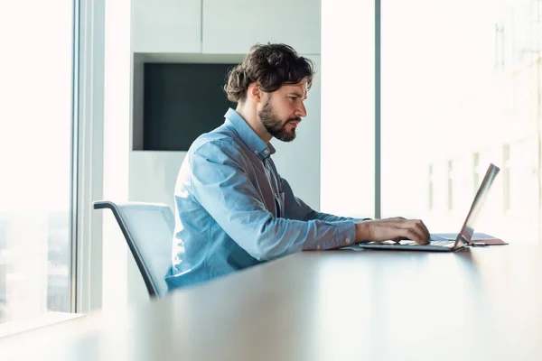 Affärsman med bärbar dator sitter vid skrivbordet i moderna kontor — Stockfoto