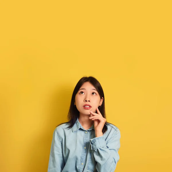Pensativo jovem ásia senhora no casual desgaste olhando para cópia espaço sobre amarelo estúdio fundo — Fotografia de Stock