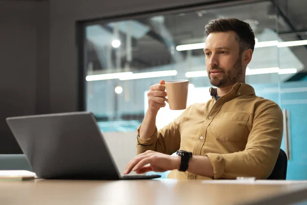Empresário usando laptop e beber café trabalhando sentado no escritório — Fotografia de Stock