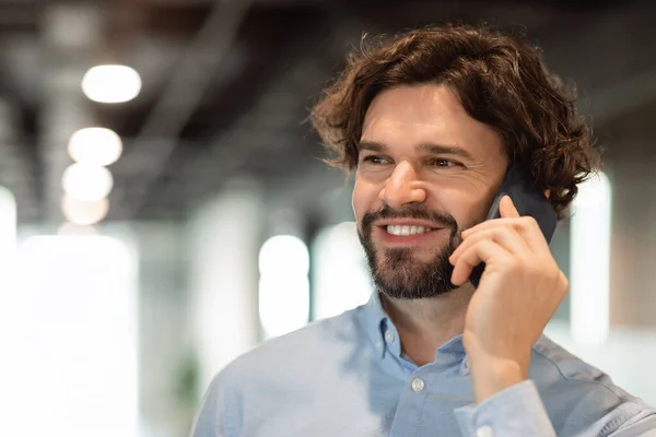 Uomo d'affari sorridente che lavora e parla al cellulare in ufficio — Foto Stock