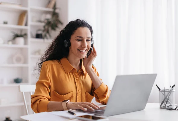 Femme heureuse portant casque vidéo appelant sur ordinateur portable sur le lieu de travail — Photo