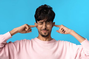 Sinirli genç Hintli adam kulaklarını kapatıyor.