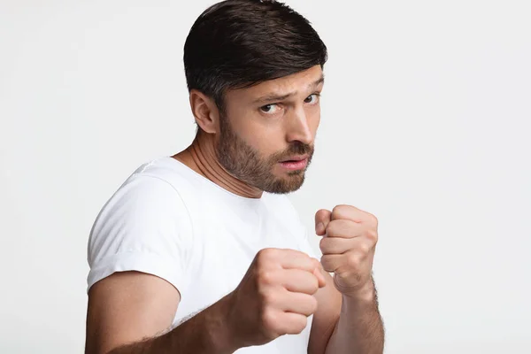 Hombre determinado apretando puños listo para luchar sobre fondo blanco — Foto de Stock