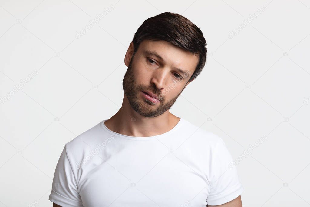 Portrait Of Upset Bearded Man Bowing Head Over White Background